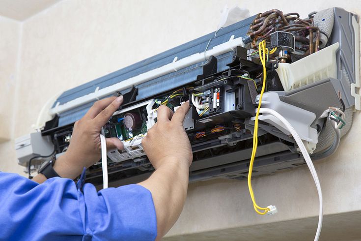 Technician repairing an air conditioning unit, showcasing HVAC repair services relevant to Dycus Heating and Air Conditioning in Manteca, CA.