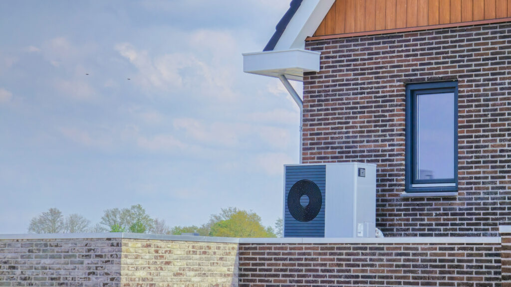Air source heat pump unit installed outdoors on a brick wall, emphasizing HVAC solutions for winter comfort in Modesto.