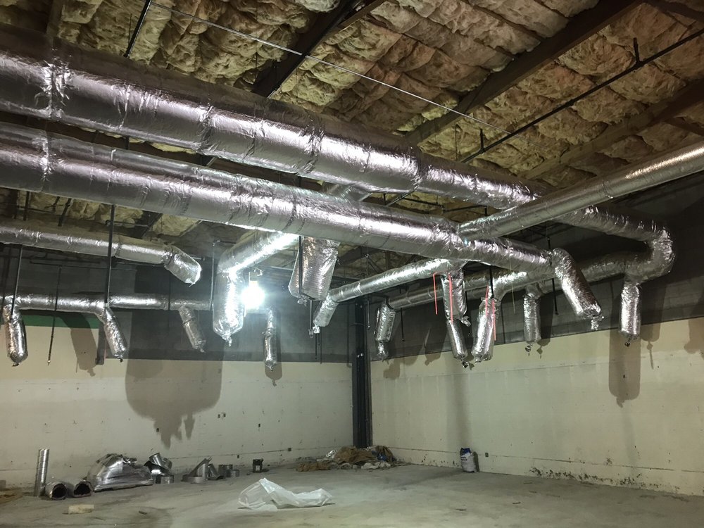 HVAC ductwork installation in a commercial space, showcasing insulated metallic ducts suspended from the ceiling, reflecting Dycus Heating & Air Conditioning's services for efficient heating and cooling solutions in Manteca, CA.