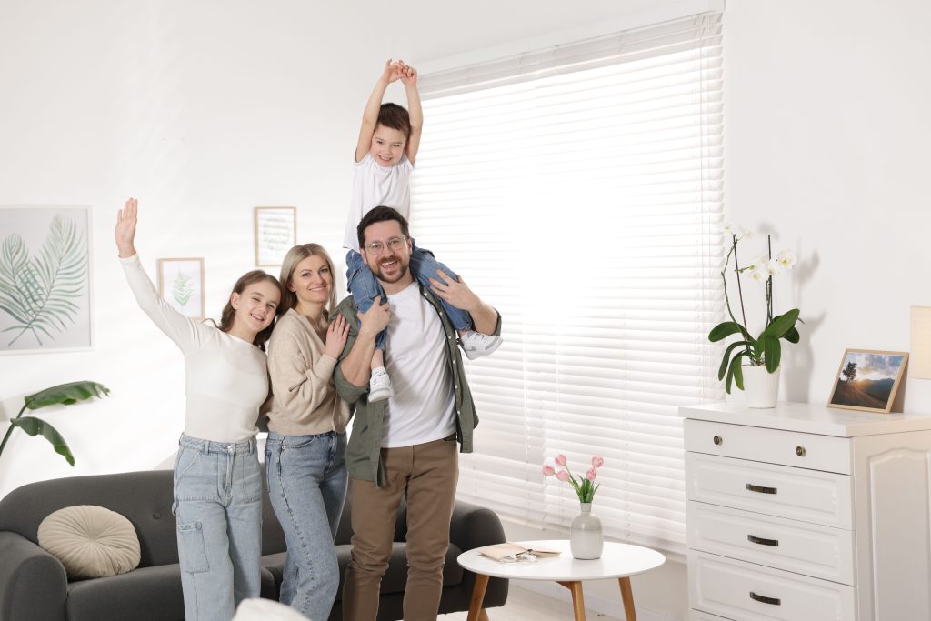 Happy family of four posing together at home, showcasing warmth and togetherness in a cozy living space, emphasizing comfort and family life in Modesto.