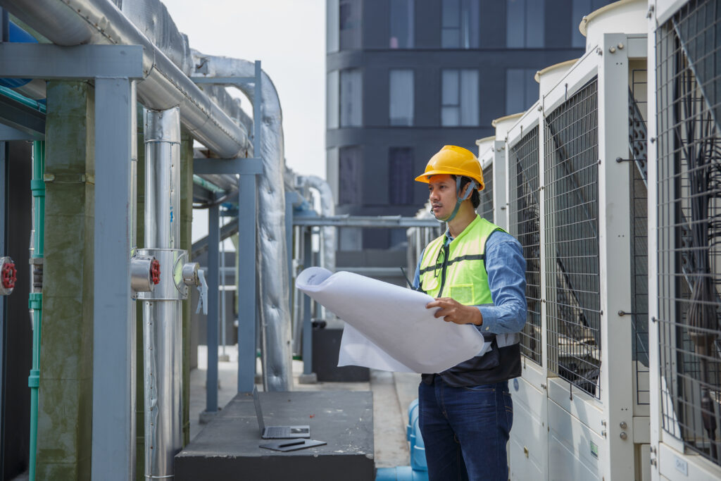 Commercial HVAC technician reviewing installation plans next to rooftop units, emphasizing professional HVAC installation services in Modesto, CA.