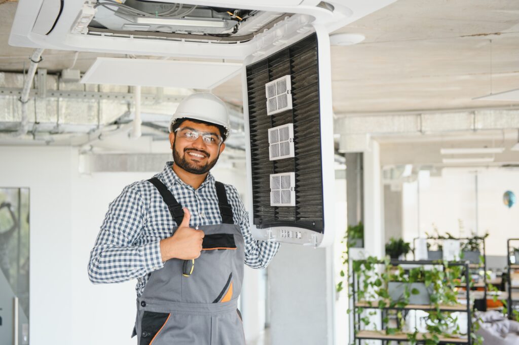 Maintenance technician repairing commercial HVAC system indoors, showcasing expertise in air conditioning service for businesses in Modesto, CA.