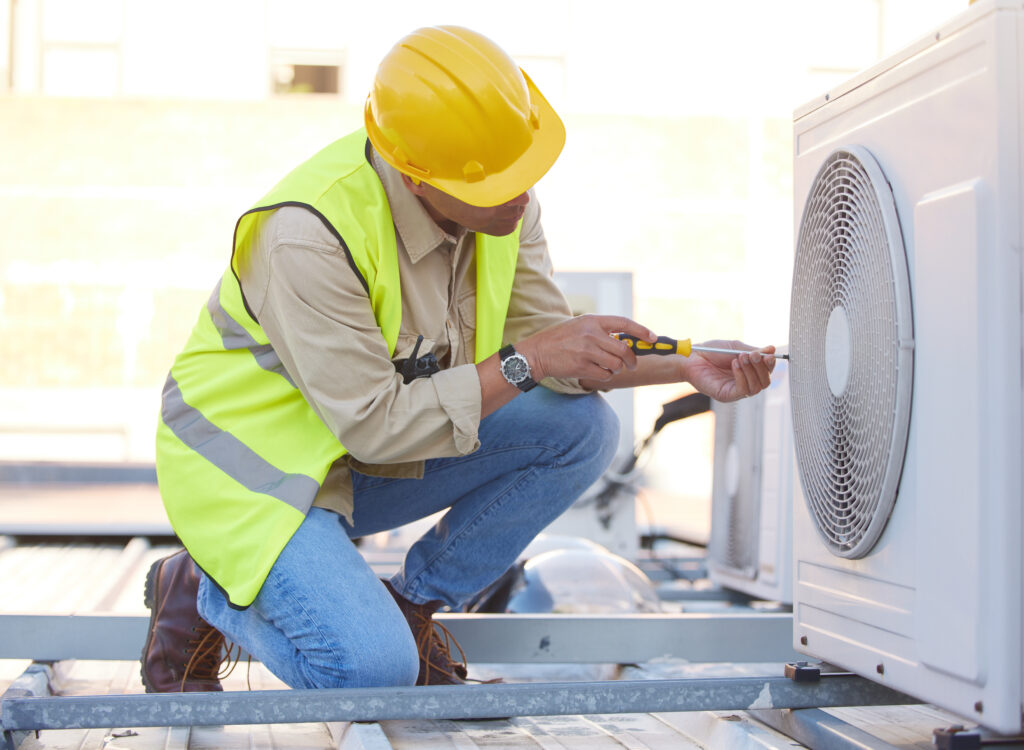 Technician in safety gear repairing heat pump on rooftop, emphasizing expert installation and maintenance services for energy-efficient heating and cooling in Modesto, CA.